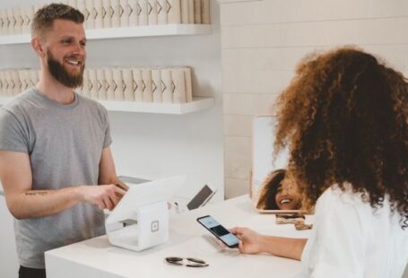 Customer - man in grey crew-neck t-shirt smiling to woman on counter
