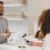 Customer - man in grey crew-neck t-shirt smiling to woman on counter