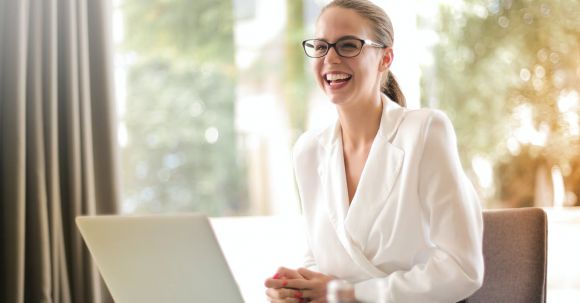 Startup Resources - Laughing businesswoman working in office with laptop