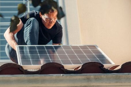 Technology Resources - A Man in Black Shirt Installing a Solar Panel on the Roof