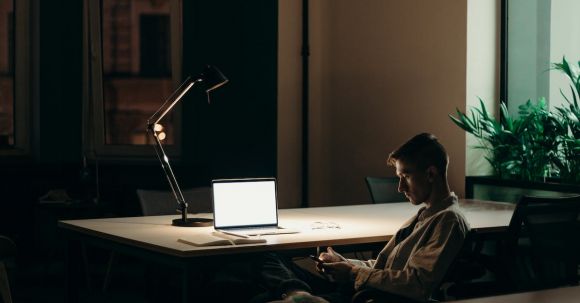 Stay Updated - Man in Black and White Plaid Dress Shirt Sitting on Chair in Front of Macbook